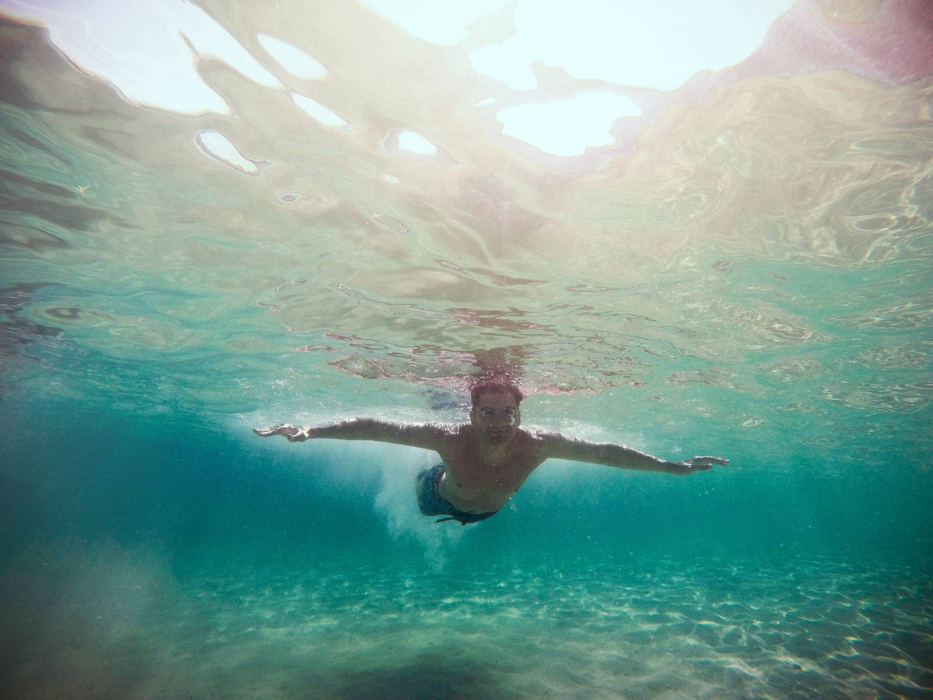 Young man with swimming goggles diving into the sea water.