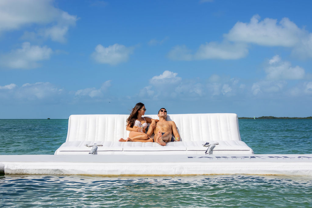 couple lounging on floating couch in the ocean